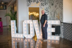 A man standing in front of "Love " Prompt